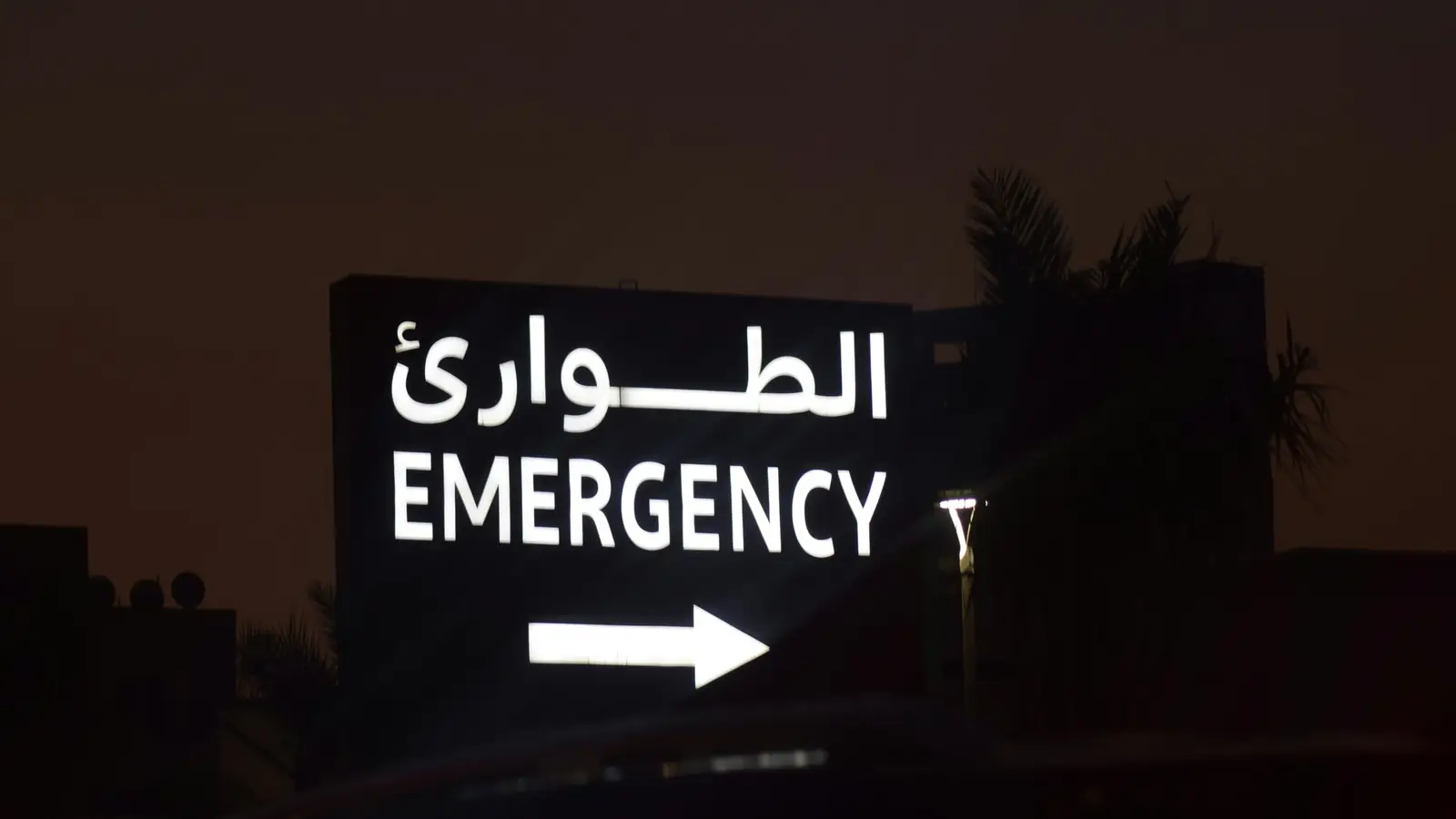 A lit hospital Emergency sign in English and Arabic