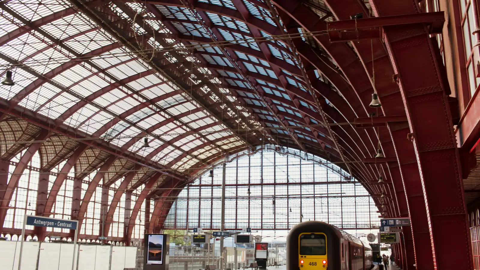 A train under the arched iron-and-glass roof of a railway station