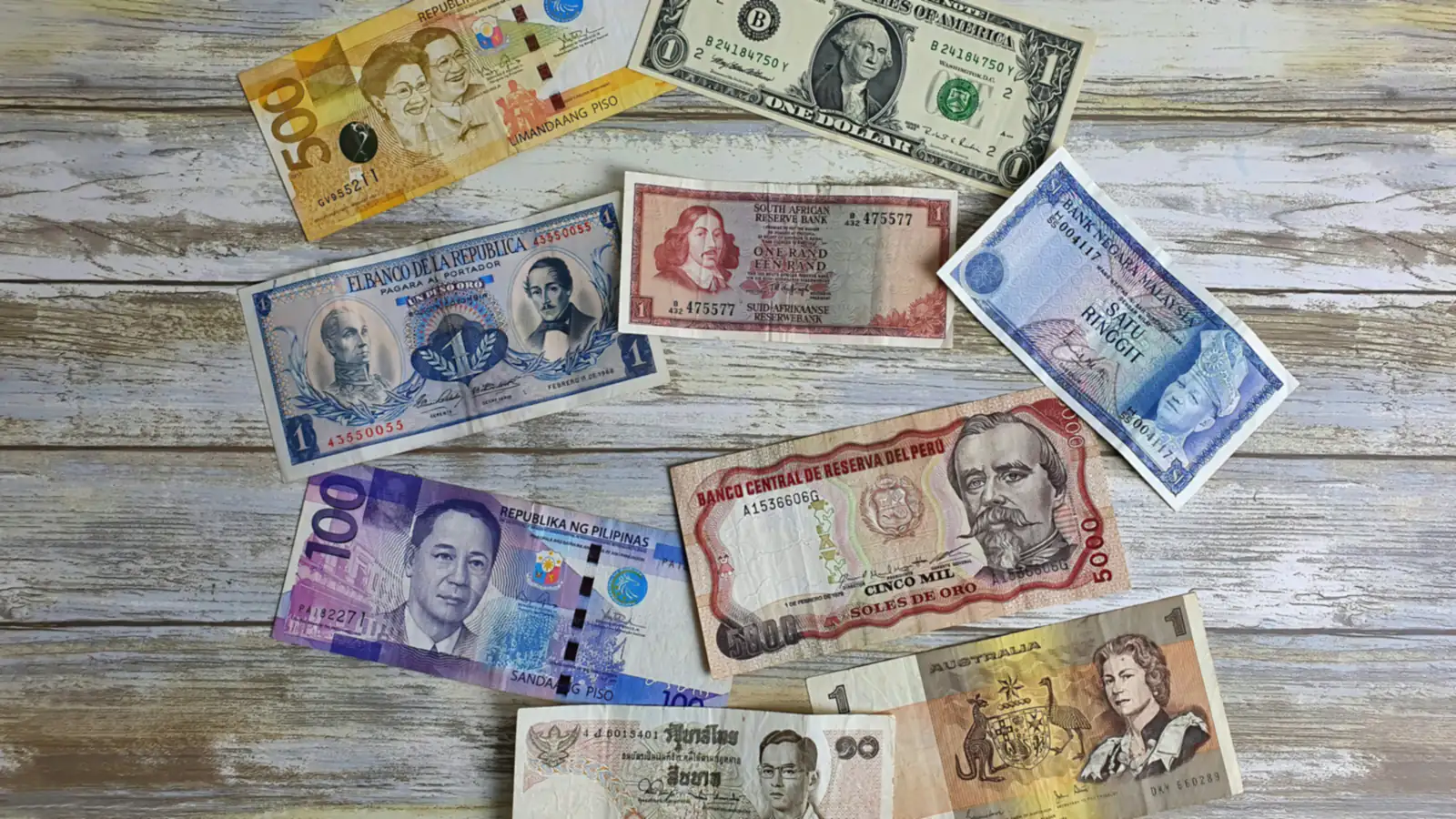 Banknotes from several countries spread on a wooden table