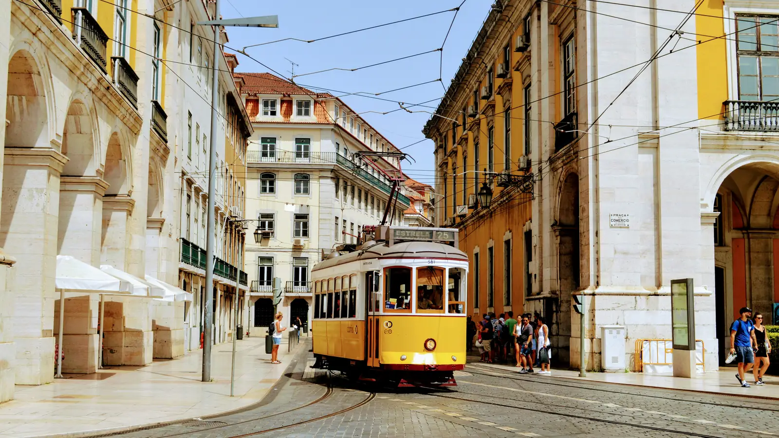 A yellow tram on a street of historic buildings in Lisbon