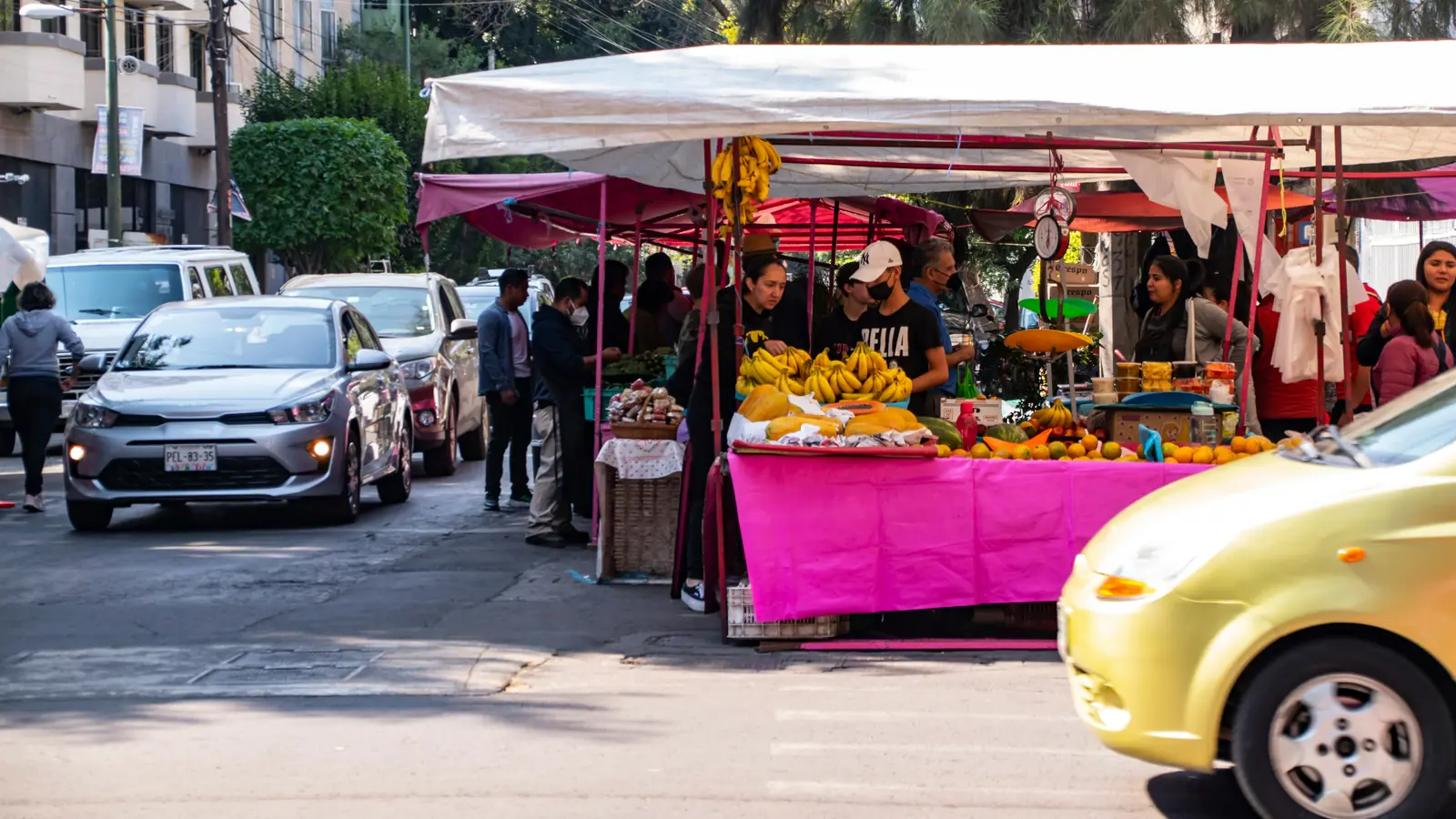 A street fruit stall in Mexico City, with cars passing