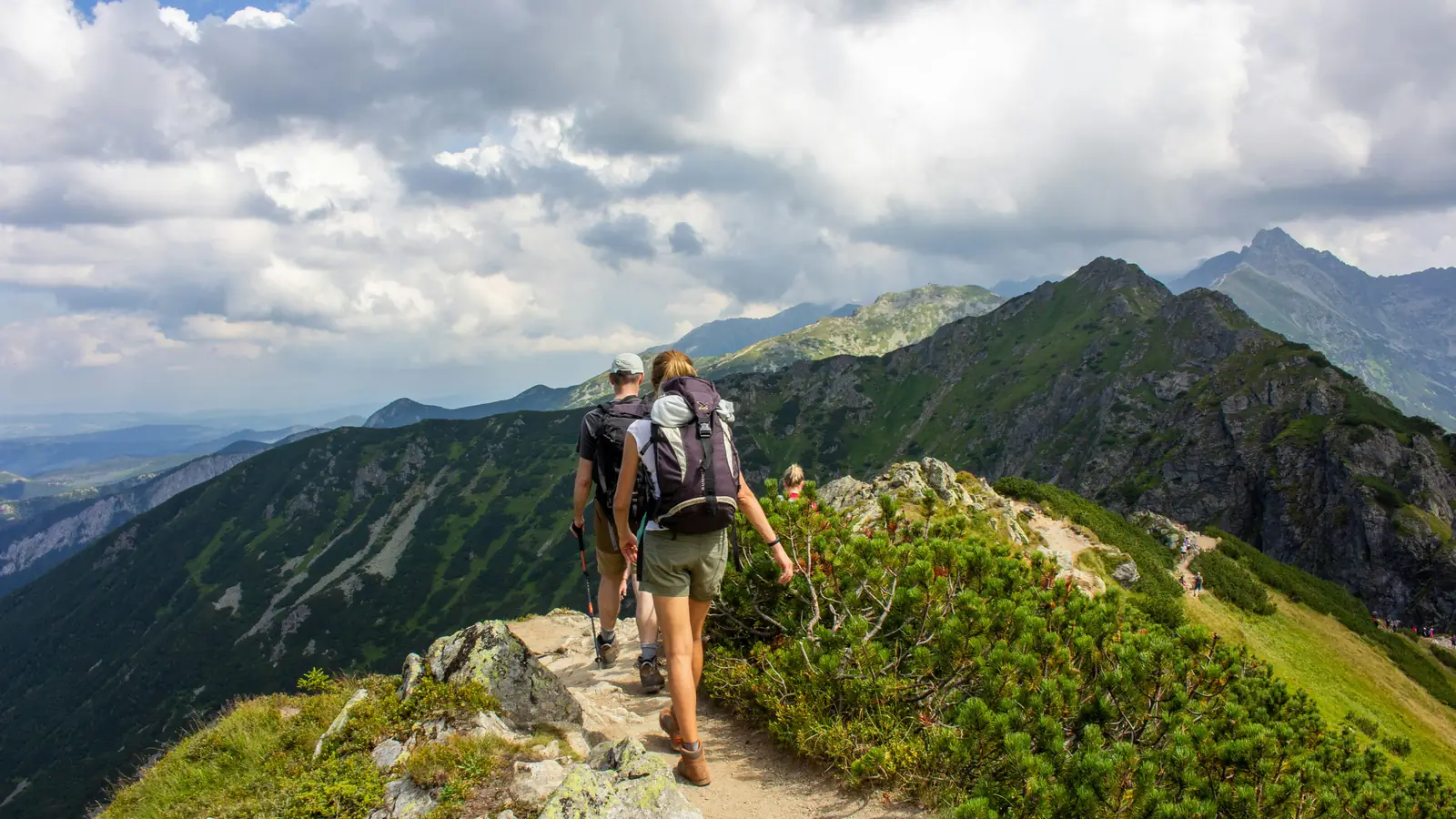 Two hikers with backpacks on a mountain ridge trail in the Tatras