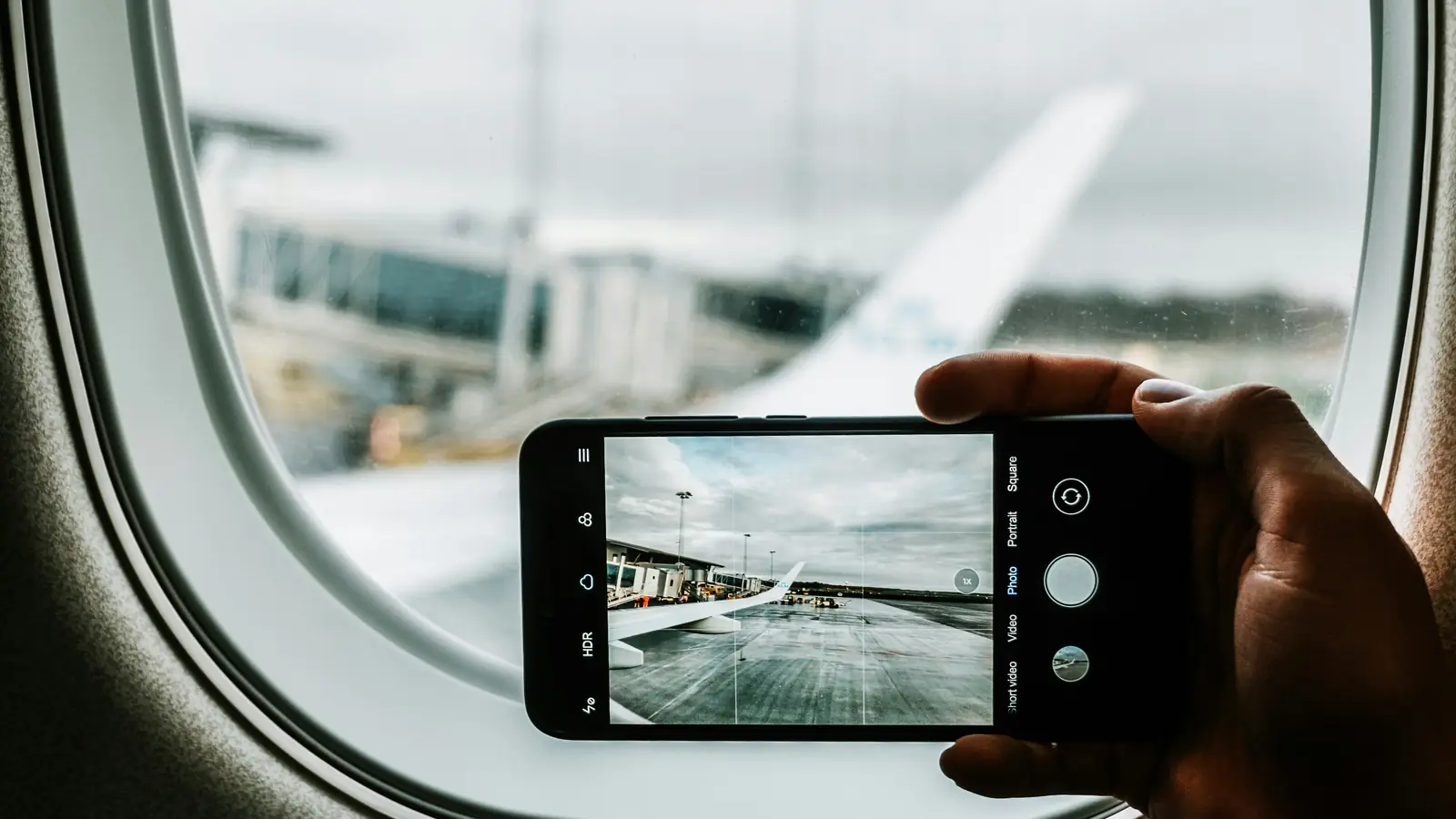 A phone held up to an aircraft window at the airport