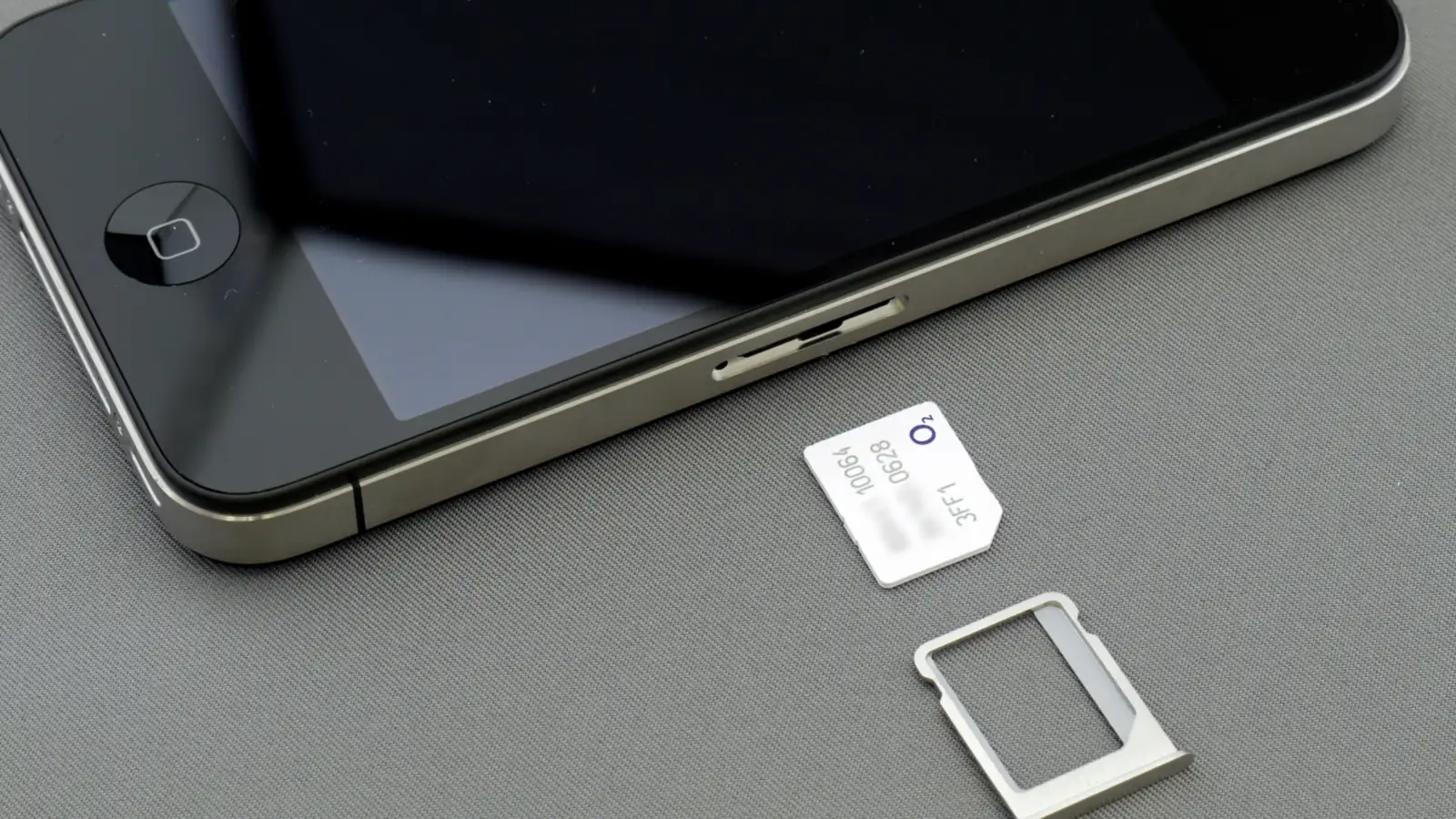 A phone with its SIM tray pulled out and a nano-SIM card beside it