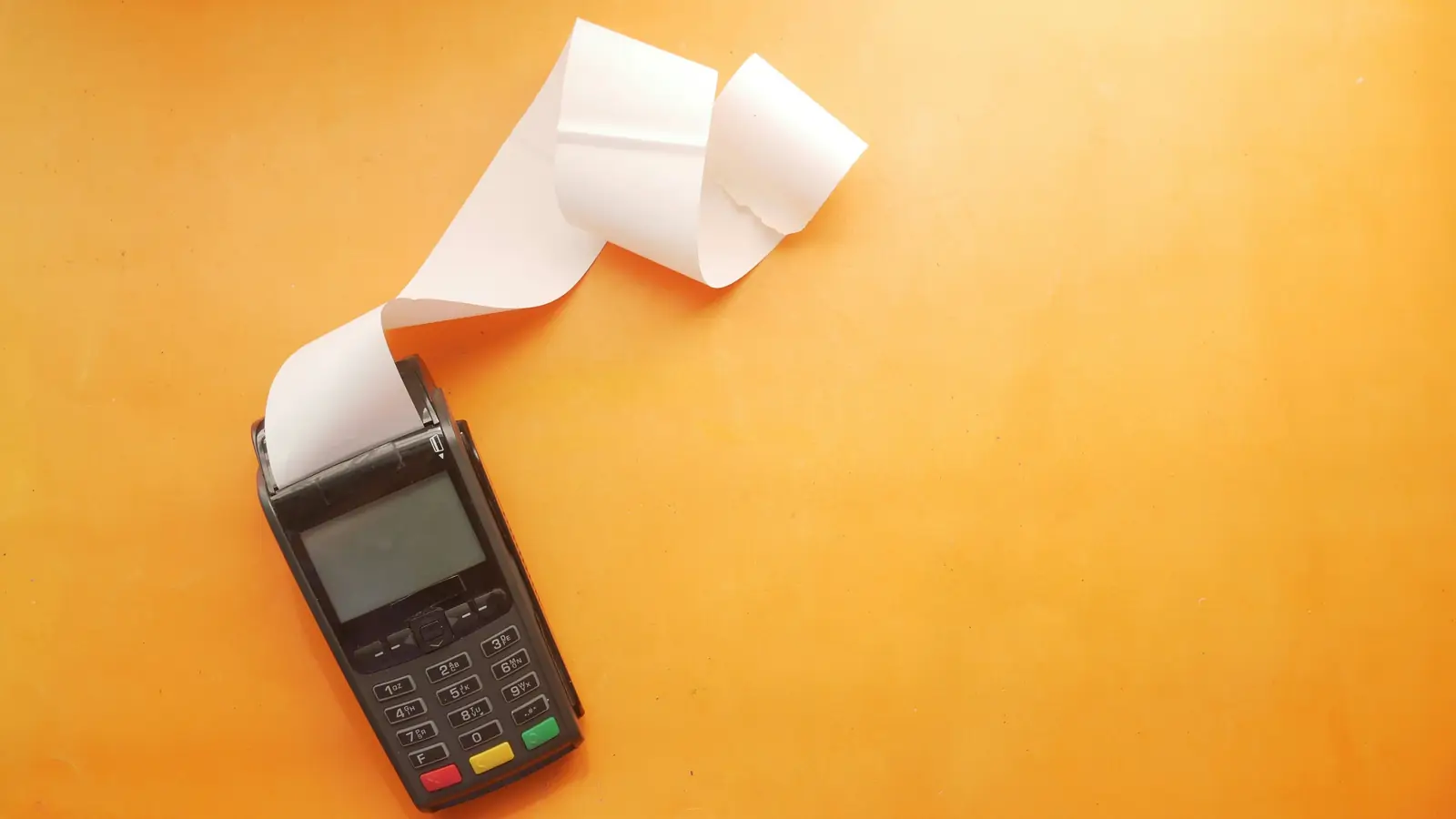 A card payment terminal printing a long paper receipt