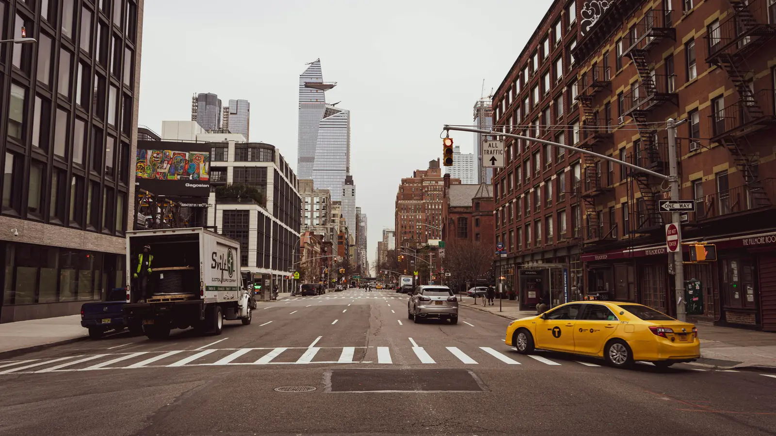 A Manhattan street with a yellow taxi at the crosswalk